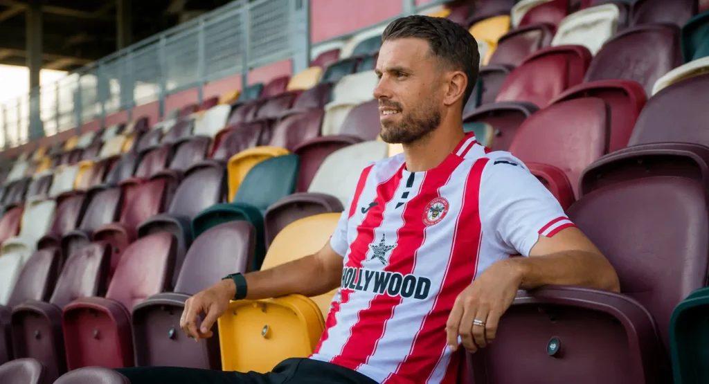 Jordan Henderson wearing a Brentford shirt while sitting in the stadium stands as Chelsea reportedly lead the race to sign the experienced England midfielder.